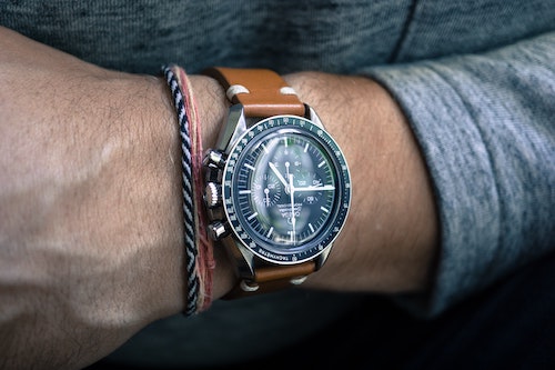 Photo of a man's wrist wearing a luxury wrist watch with a brown leather strap.