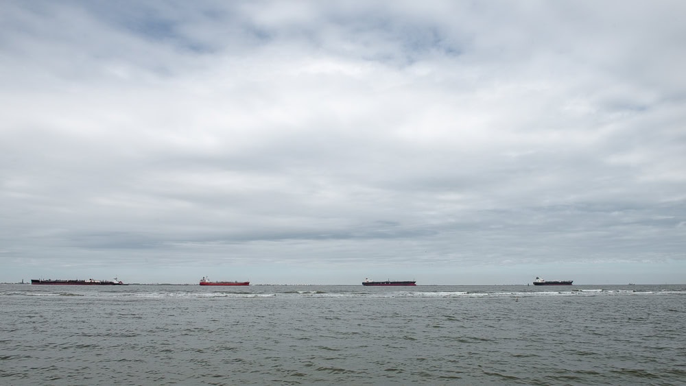 A line of four ships waiting on a cloudy day to enter Galveston Bay and the Houston Ship Channel. Photo ©Jeff Kauffman.
